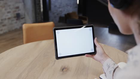 caucasian casual businesswoman making video call using tablet with copy space in office, slow motion