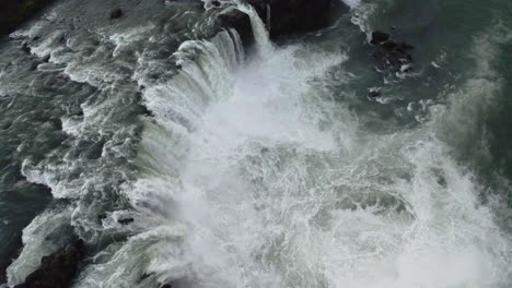 drone hovering over a large circulair waterfall with the camera tilting down slowly in iceland in 4k