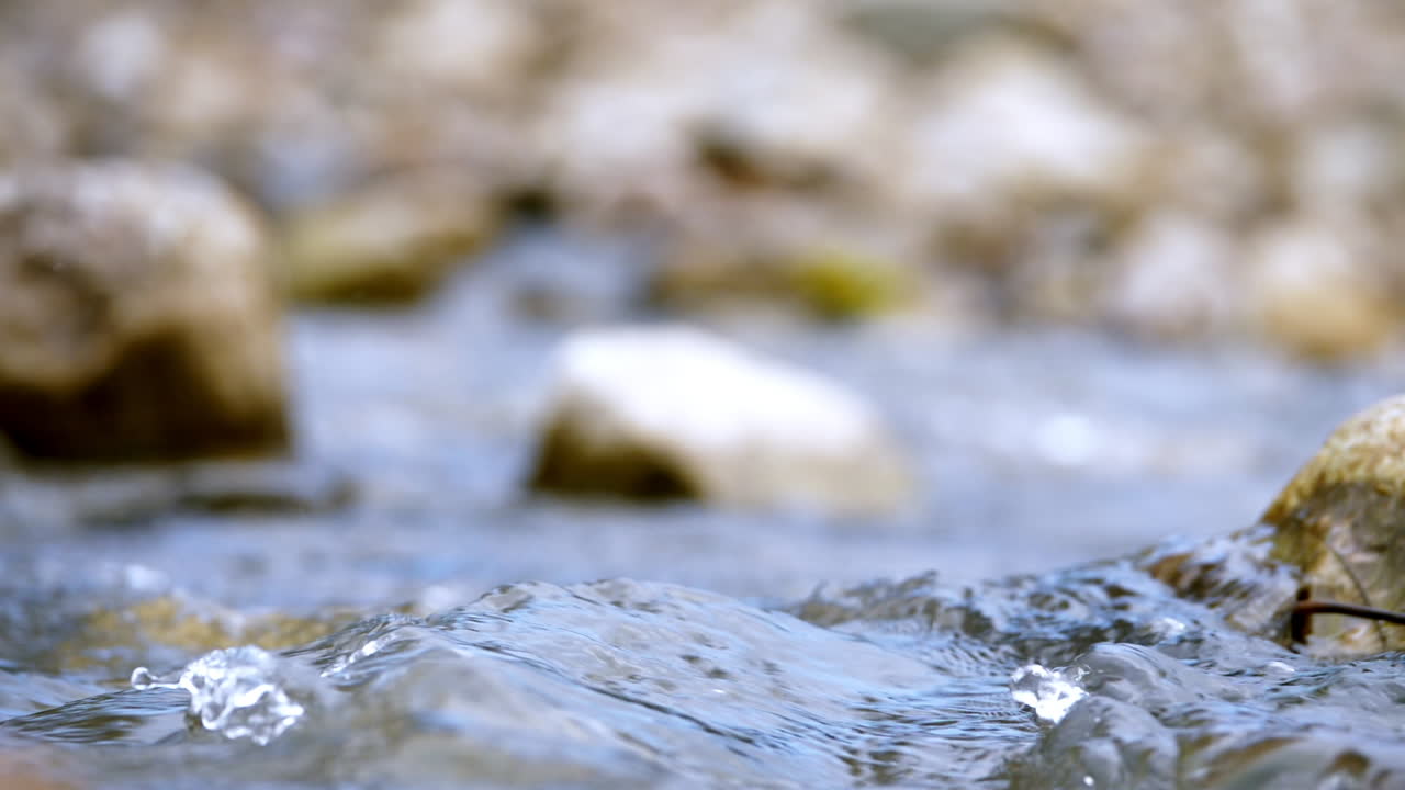 Clear stream running through stone boulders Abundant river flowing in slow motion