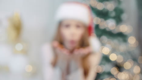 Portrait-of-happy-woman-blowing-confetti-in-santa-hat.