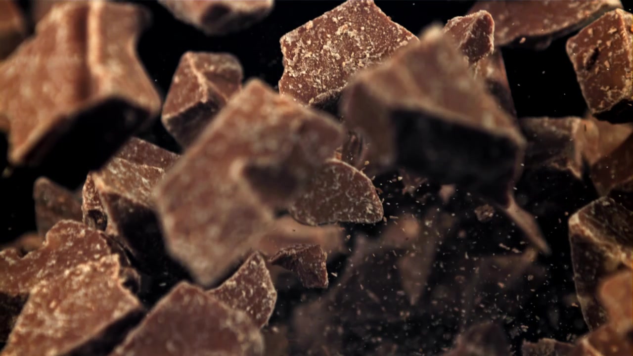 Movimento rallentato: pezzi di cioccolato che cadono su sfondo nero.