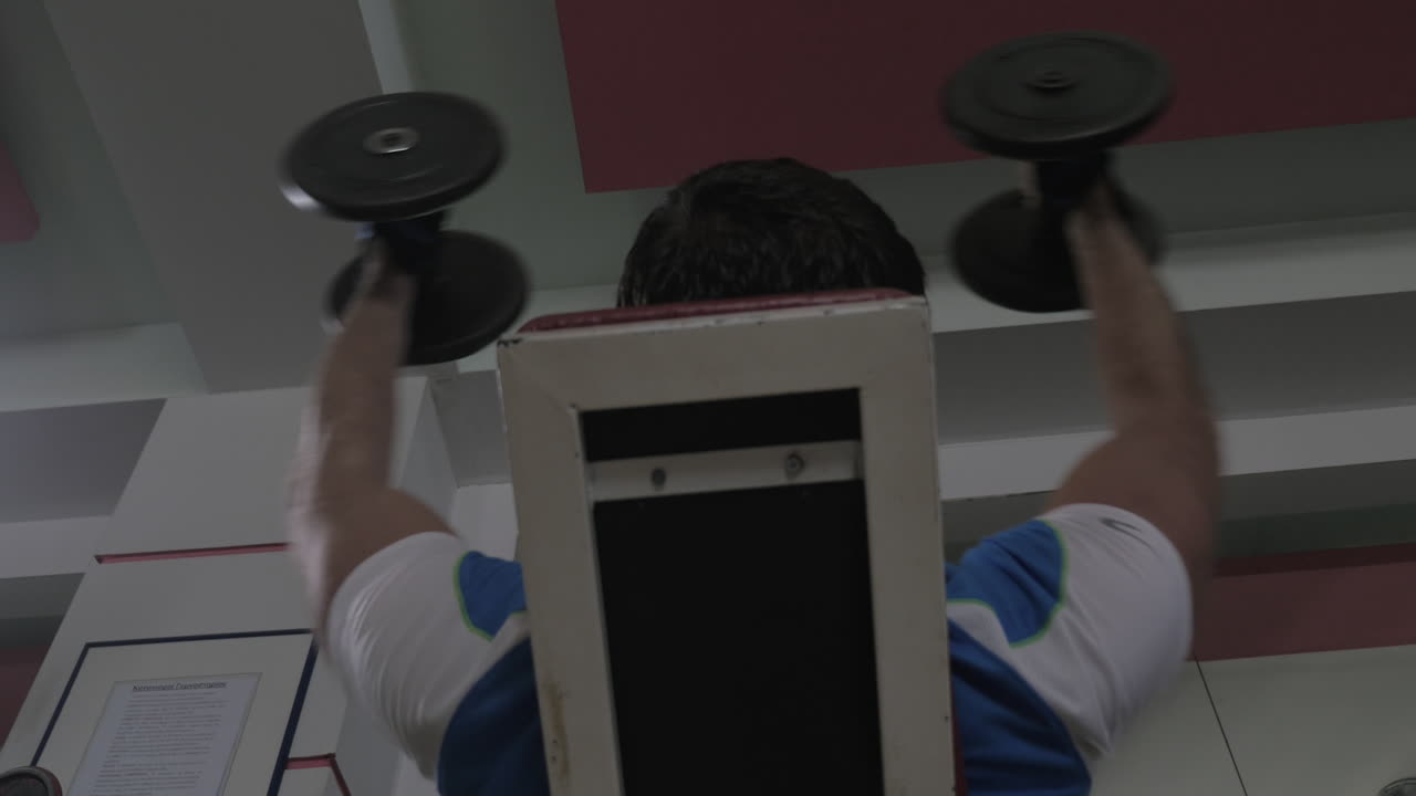 체육관에서 덤벨을 들고 훈련하는 남자