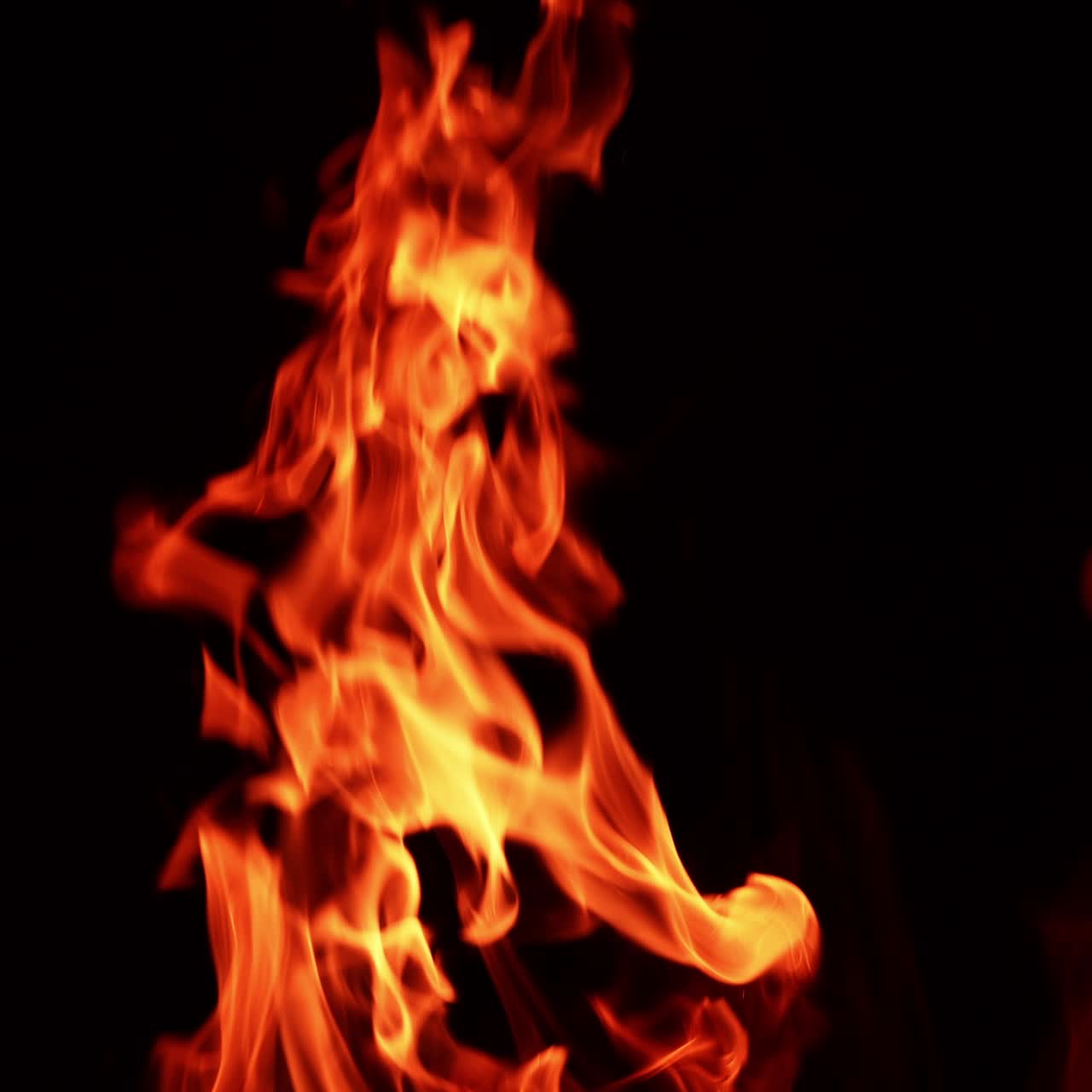 Red flame moving in the darkness. Top part of a bonfire isolated at black backdrop. Close up
