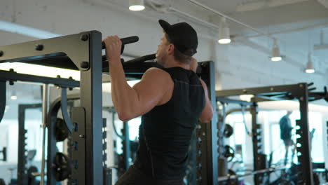hombre de fitness natural bombeando músculos haciendo ejercicios de pull-ups en el gimnasio