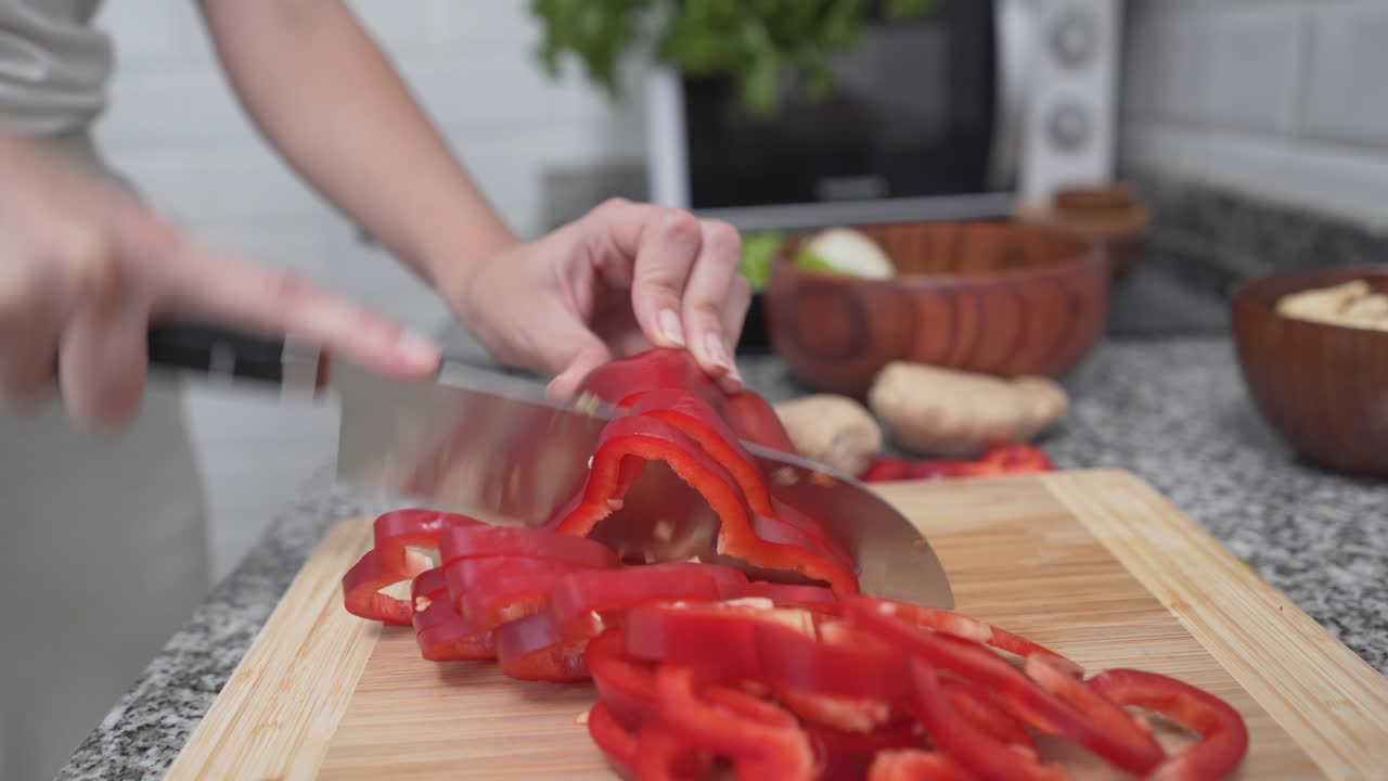 Woman chopping a red bell pepper