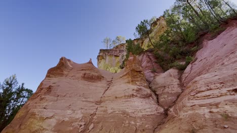 ocher rocks with different layers of color in the evening light with some trees in france nature conservation