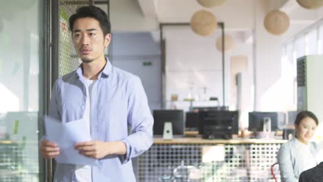 asian businessman reading a report while walking in office