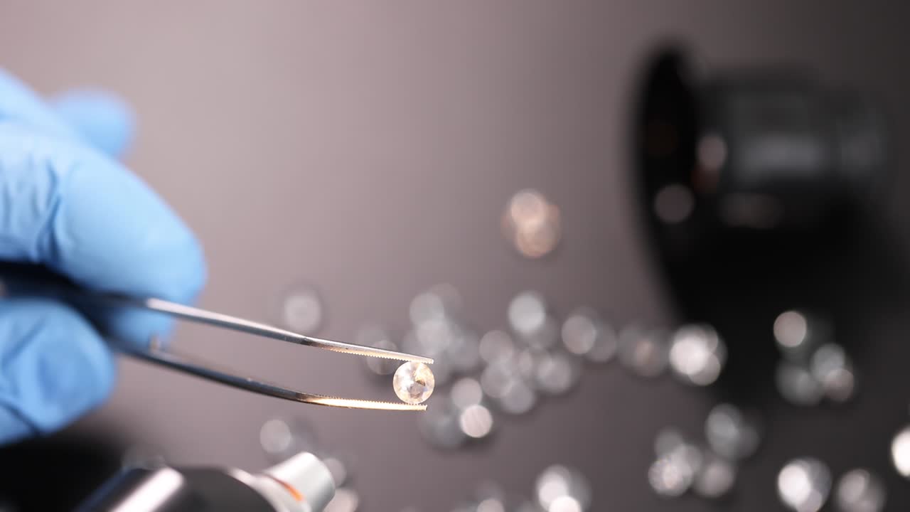 joyero sosteniendo un diamante con pinzas en el taller de primer plano película 4k en cámara lenta