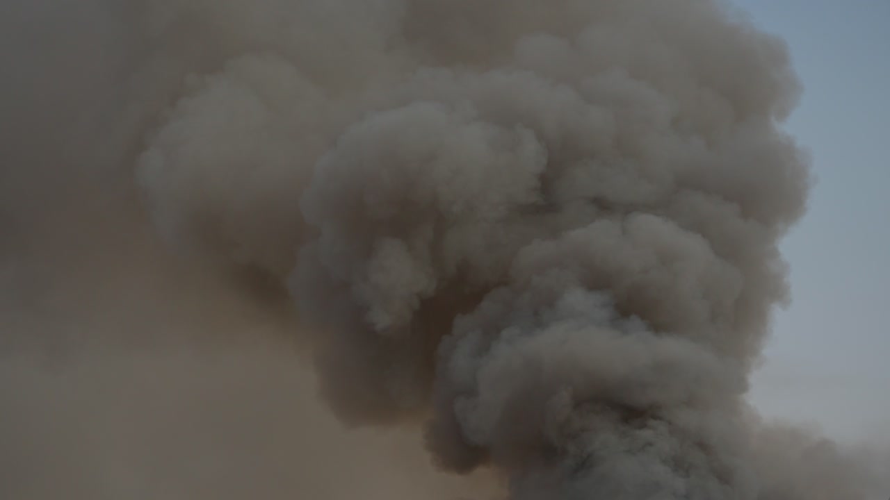 Black smoke clouds and flames rise into the sky.