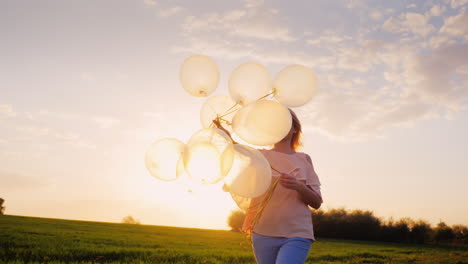 Sorglose-Junge-Frau-Mit-Luftballons,-Die-Bei-Sonnenuntergang-Auf-Einer-Grünen-Wiese-Spaziert-1