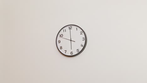 a minimalist wide shot of a black and white wall clock against a white background, showing the time at 6:00.