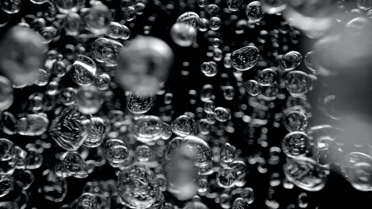 Air Bubbles Rising From The Bottom Up In The Black Underwater Abyss in Macro and Slow Motion, Top View