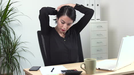 atractive female office worker tying hair up at the desk