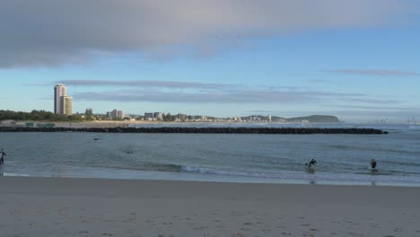 Surfers-Walking-Out-From-The-Ocean-In-Currumbin-Beach---Gold-Coast,-Queensland---wide-shot