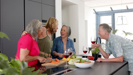 senior diverse group of women share a laugh in a modern kitchen while preparing a meal