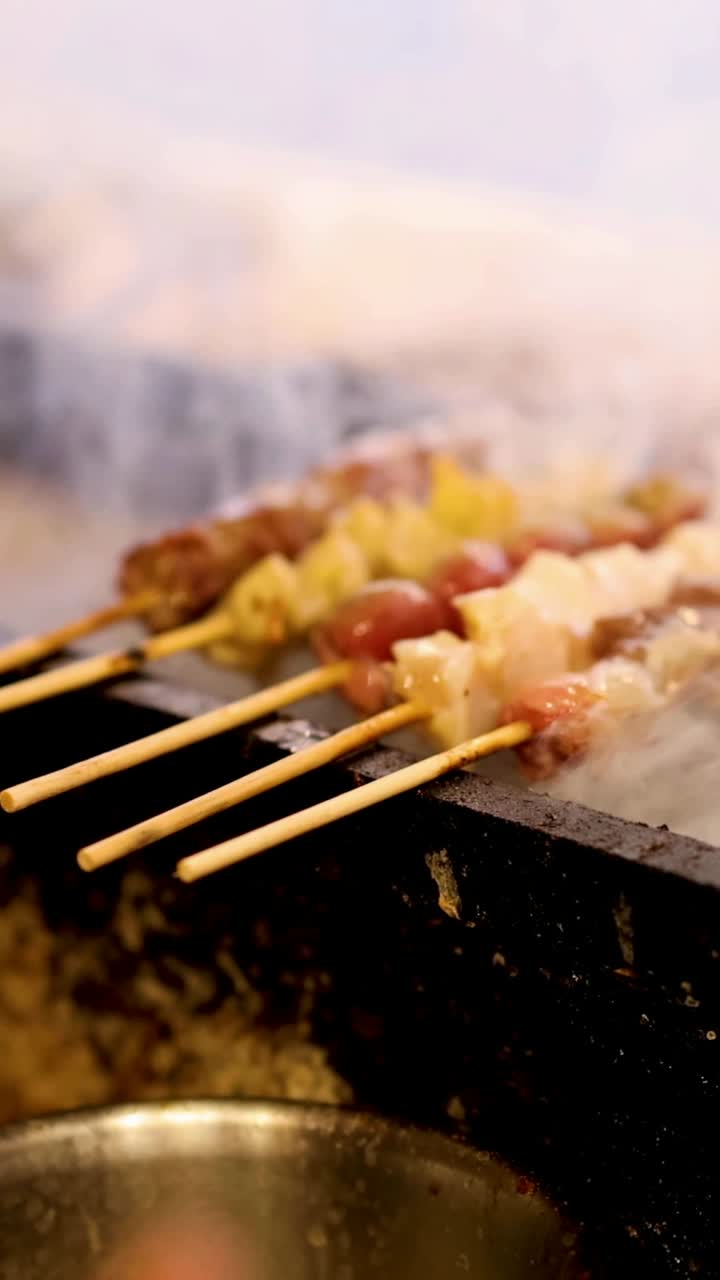 Mani che cucinano spiedini di carne su un barbecue fumante