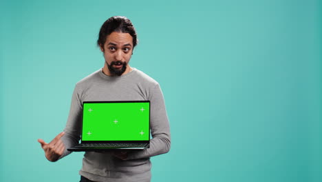 hombre presentando una pantalla verde portátil, aislado sobre el fondo del estudio