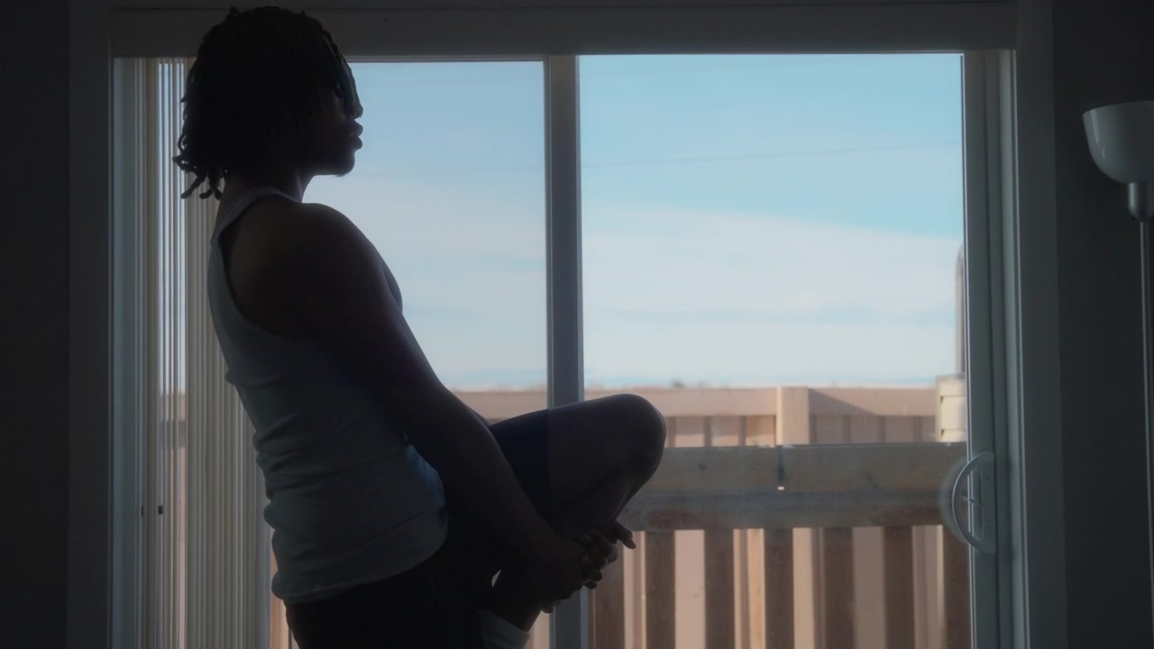 Young man stretching his legs in front of a window