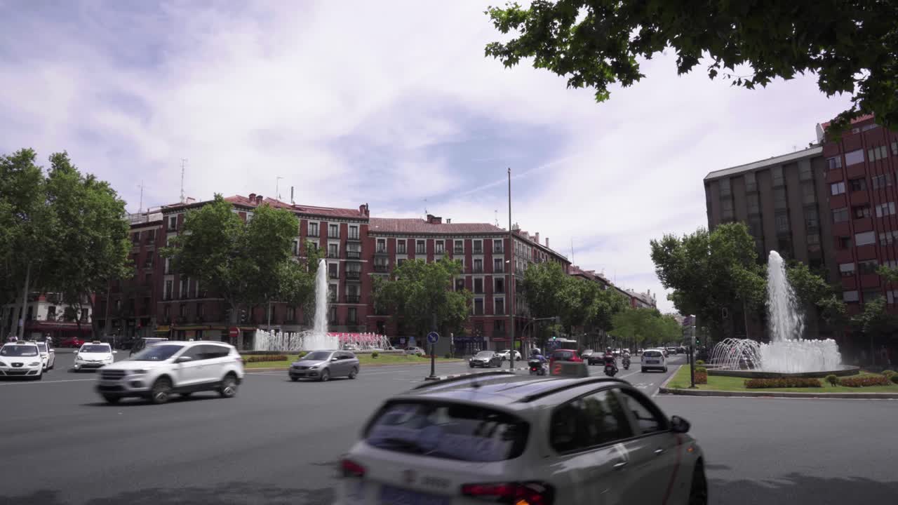 Cars passing by San Bernardo fountain in Madrid, Spain
