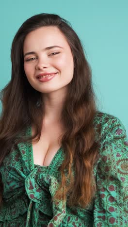happy young woman showing thumbs up in blue studio
