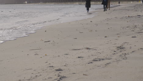 people walking in the beach with ocean waves in gdynia, poland