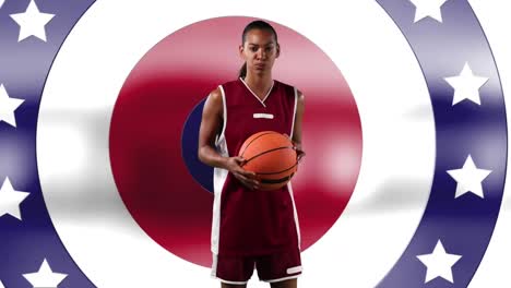 african american female basketball player holding basketball against stars on spinning circles