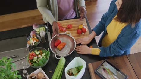 High angle video of diverse couple preparing food using tablet and composting vegetables in kitchen