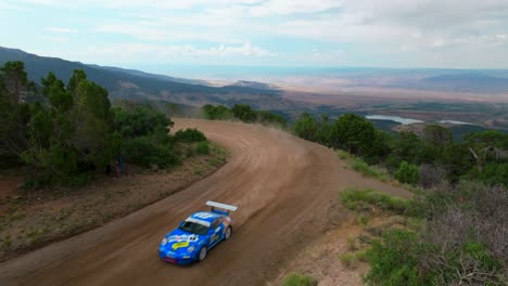 lands end hill climb rally racing jeff swart racer grand mesa grand junction colorado static sunny gray clouds blue sky blue porsche flag dirt road car speed drift turn high speed check finish line