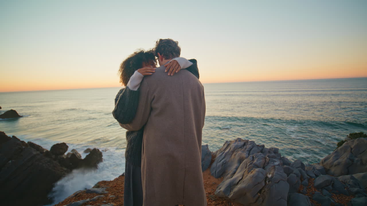 Enamoured couple hugging together at beach vacation at evening sea background