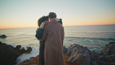 enamoured couple hugging together at beach vacation at evening sea background