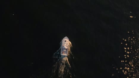 bird's eye view of a yacht sailing in a dark blue sea with foam around it