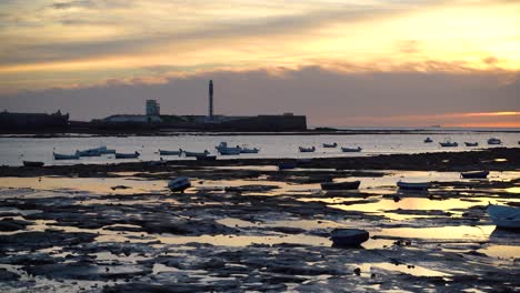 boats softly moving in ocean at low tide with light house