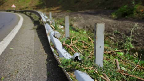 guardrail ripped off of metal support beams on side of road from mudslide that tore trees off hill