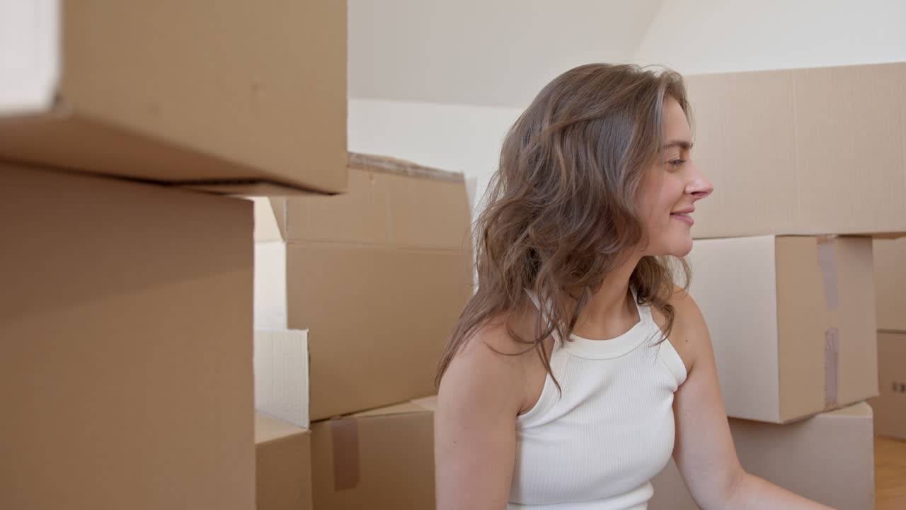 Happy brunette woman holding keys of new home with unpacked boxes in background