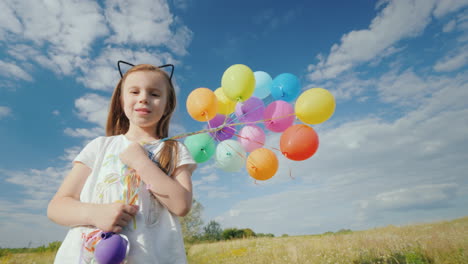 a cheerful girl with balloons is standing on a green meadow enjoy the warmth and fly of the concept