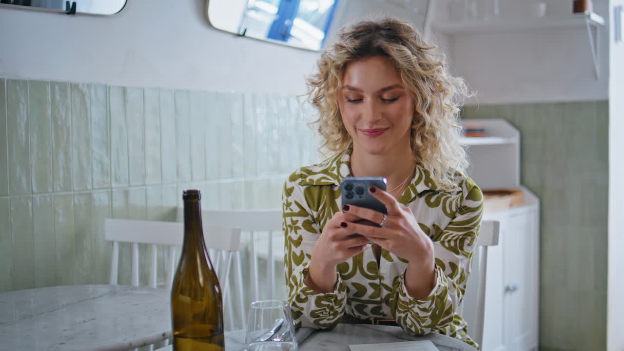 Cheerful girl messaging cellphone in cozy cafe closeup. Smiling lady reading sms