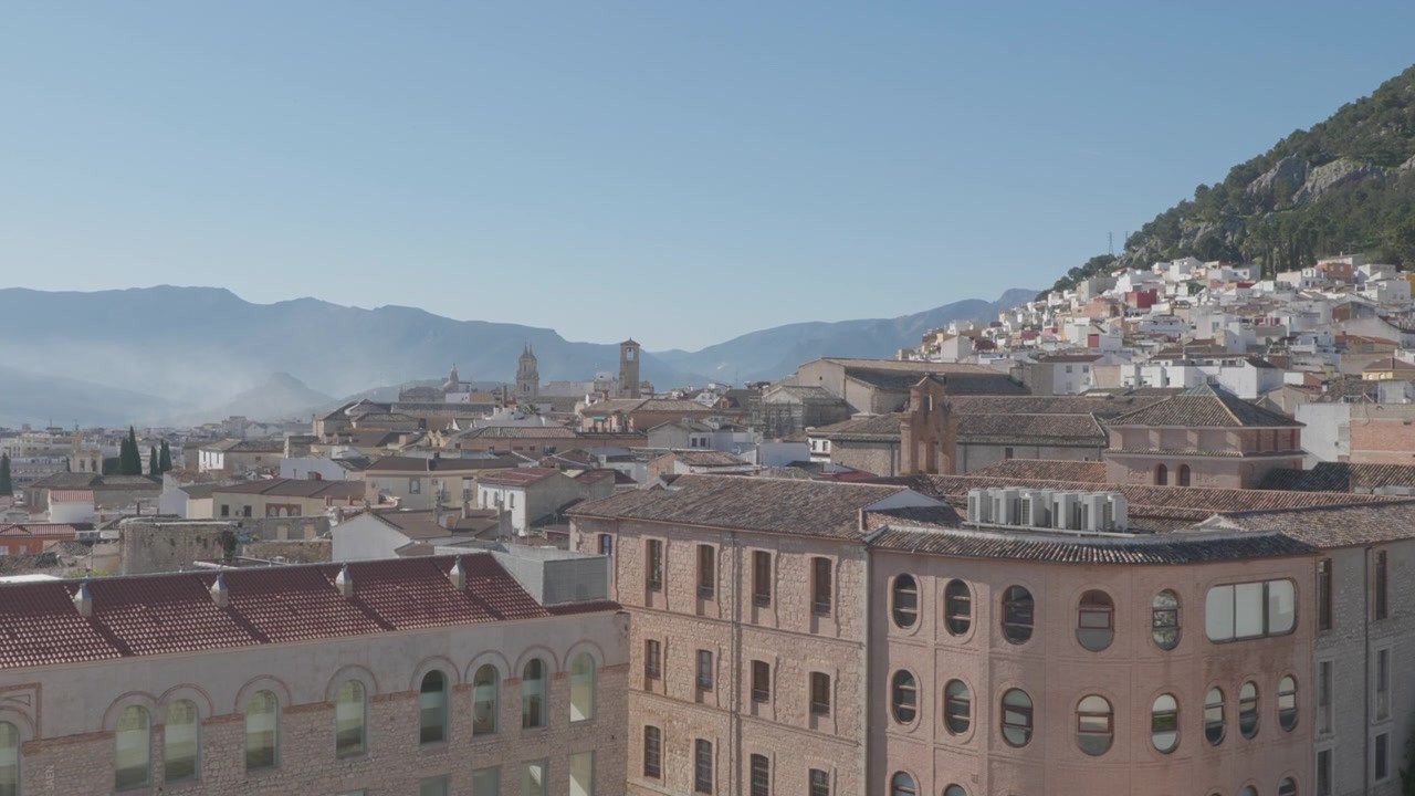 Vista panoramica dal balcone di una casa, che si affaccia su Jaén, una storica città spagnola, con case bianche e un paesaggio montuoso sullo sfondo.