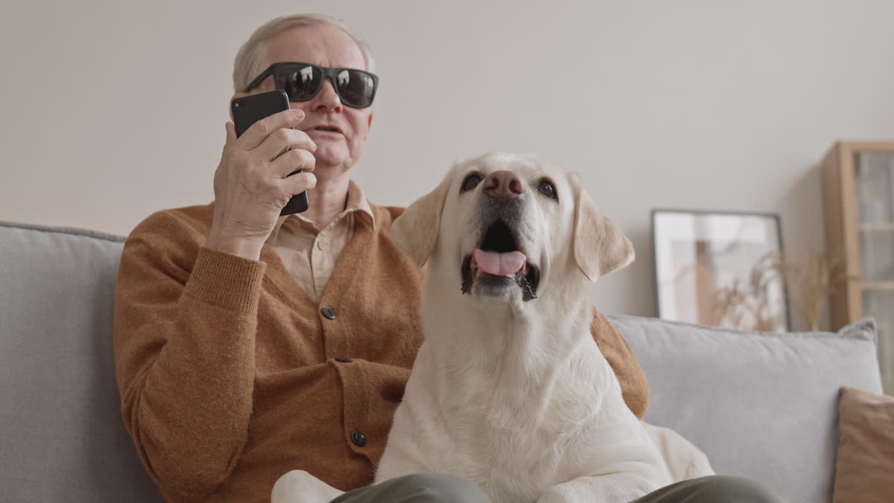 Blind Senior Man Talking on Speakerphone while Petting Dog