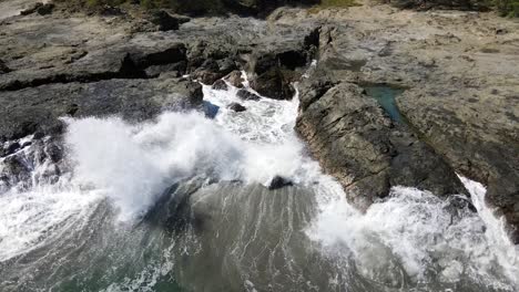 rocky stone coast with waves splashing aginst the stones drone shot filmed in costa rica