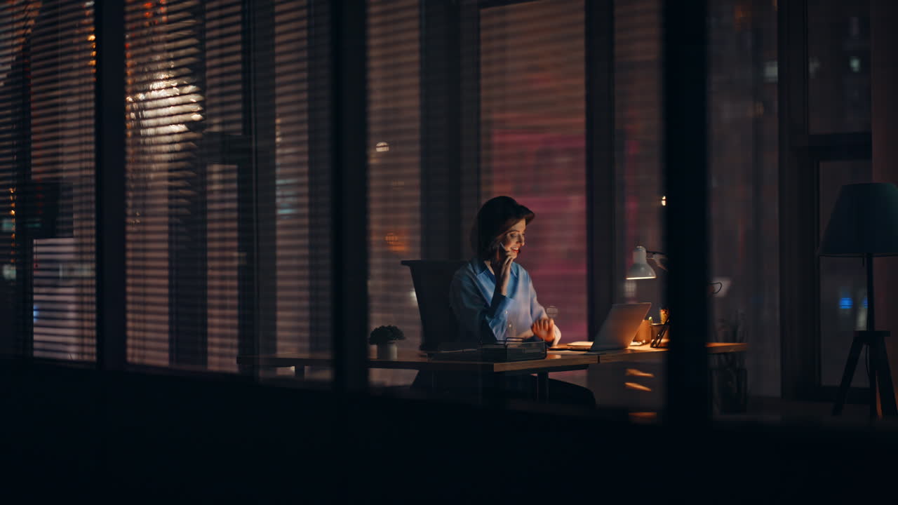 Consulente sorridente che chiama dall'ufficio di notte. Imprenditrice felice che negozia al telefono