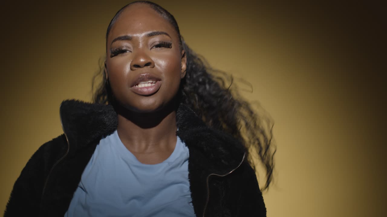 cabeza y hombros retrato de estudio de una mujer joven bailando en el centro de atención contra un fondo amarillo