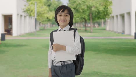 Portrait-of-Happy-Indian-school-boy-standing-with-books