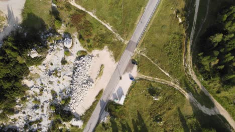 Birds-Eye-Aerial-View-of-Curvy-Pass-Road-in-Green-Landscape-of-Val-Gardena-Italy