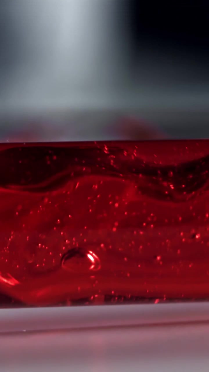 Macro Close-Up of Red Liquid with Bubbles in a Transparent Container