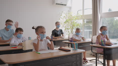 Heben-Sie-Ihre-Hand,-Um-Die-Frage-Des-Lehrers-Zu-Beantworten.-Multiethnische-Gruppe-Von-Kindern-Mit-Gesichtsmasken-In-Der-Schule-Während-Der-Covid-19-Pandemie.