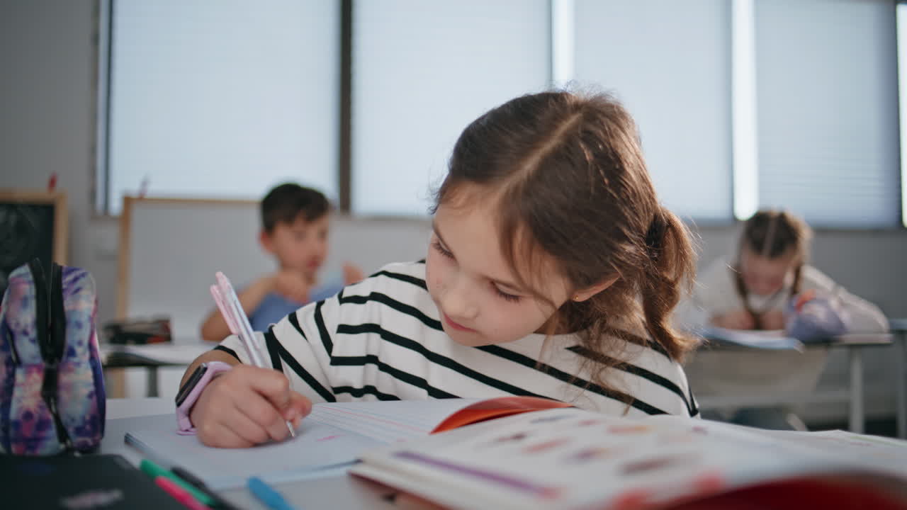 Clever schoolgirl studying classroom sitting desk closeup. Kid writing exercise