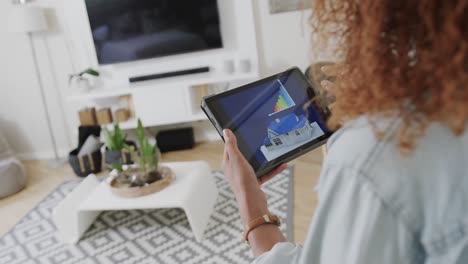 biracial woman using tablet with smart home interface on screen in living room, slow motion