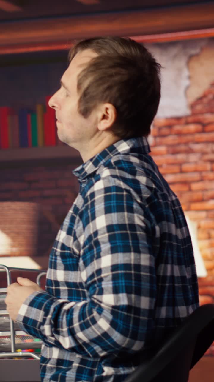 Vertical video AI engineer in home office stretching back while looking at PC screen, feeling fatigued