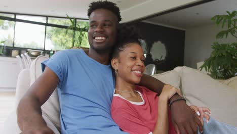 video of happy african american couple sitting on sofa and embracing
