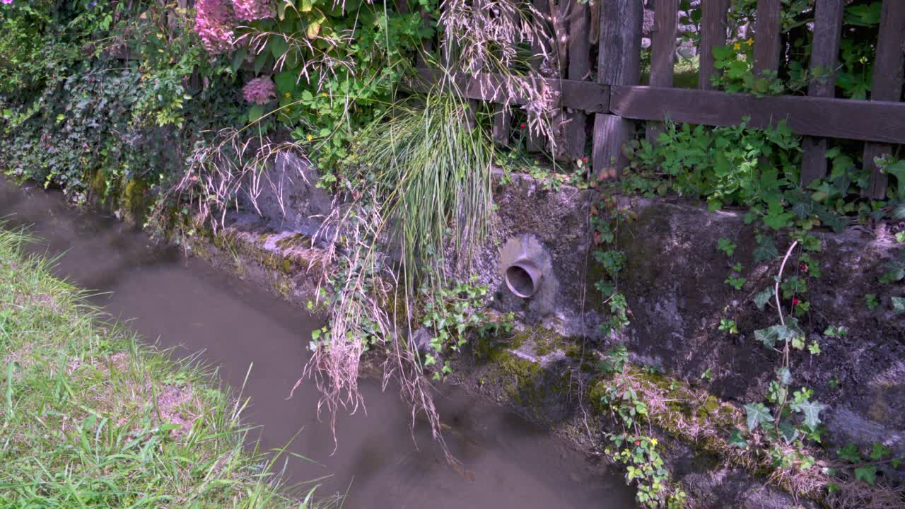 물을 원천에서 다양한 사용자에게 운반하도록 설계된 관개 채널의 일부. 벽에서 어 나온 파이프.